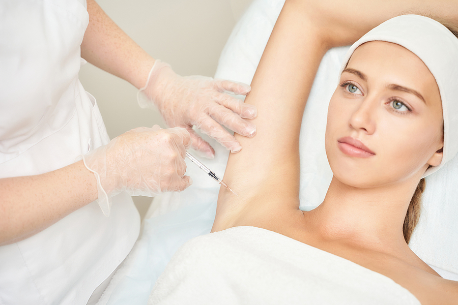 Armpit injection at spa salon. Doctor hands. Closeup view. High quality. Pretty female patient. Beauty treatment. Healthy skin procedure. Young woman head. Light background. Hyperhidrosis rejuvenation